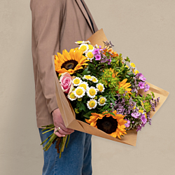 Sommer solsikkebuket med solsikker, floks, limonium, grenede krysantemum og roser bundet med pistache og hareøre – en fyldig og sæsonaktuel blomsterbuket, perfekt som gave, sommerhilsen eller blomsterlevering til hjemmet.
